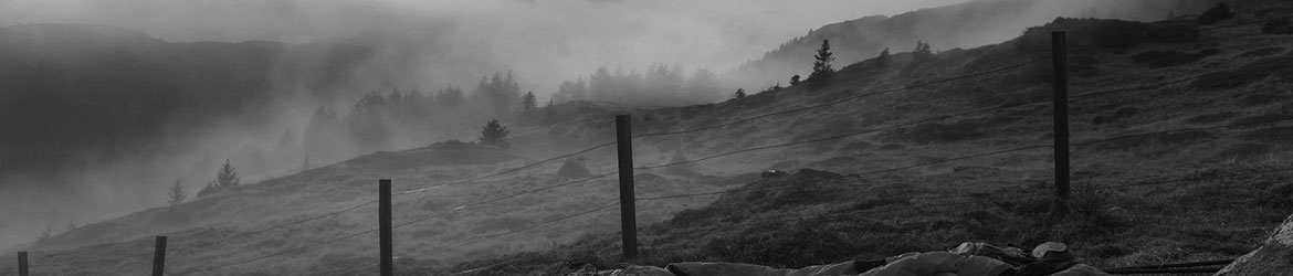Fence in the foreground of a foggy hillside