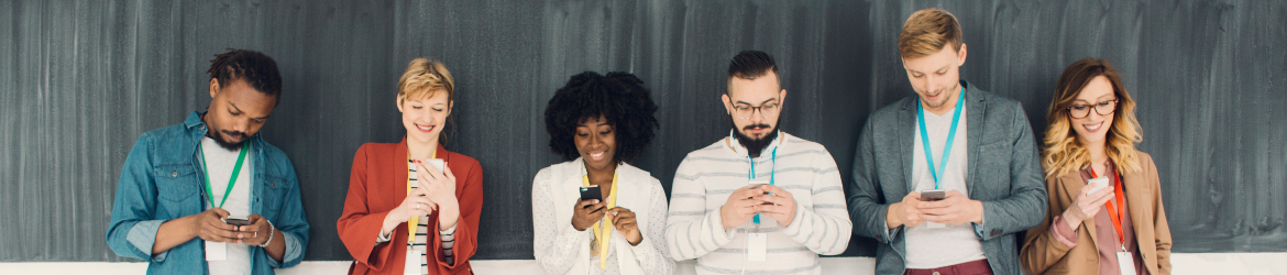 Group of people standing and looking at their phones.