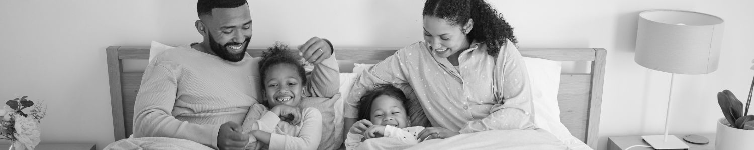 Family relaxing in bed happy and smiling.