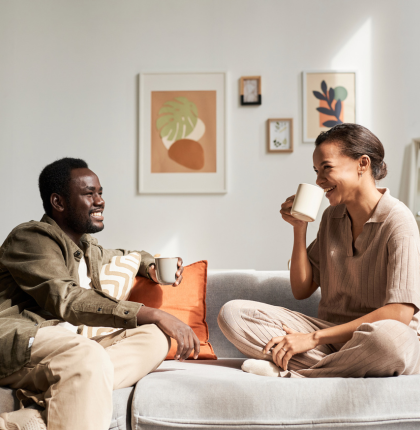 Young couple sitting on couch happy while drinking coffee.