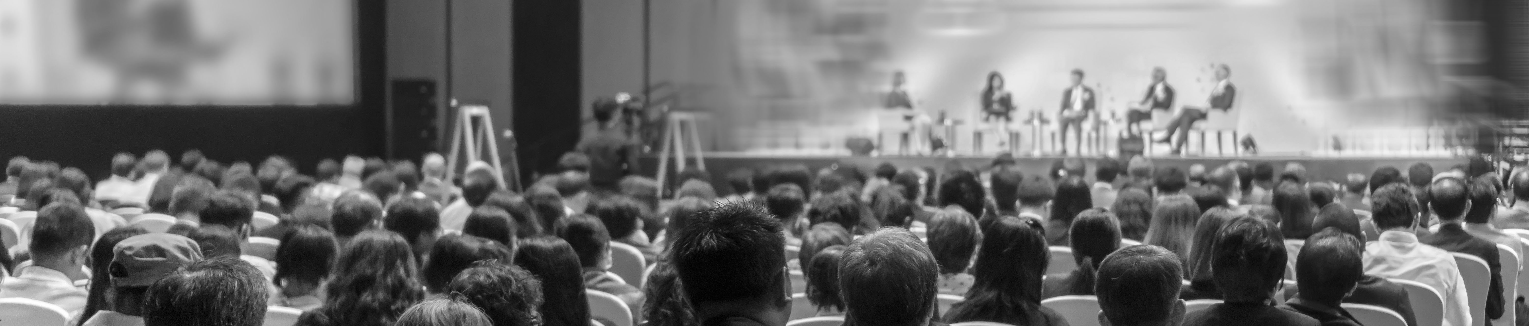 Audience faces panel of speakers on stage