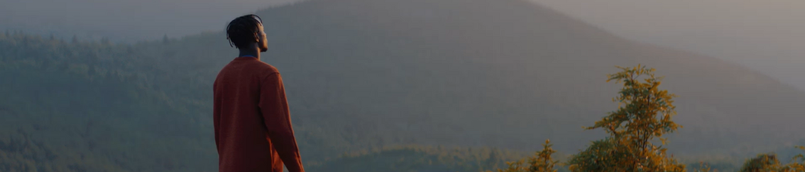 Man standing on mountain looking at sunset.