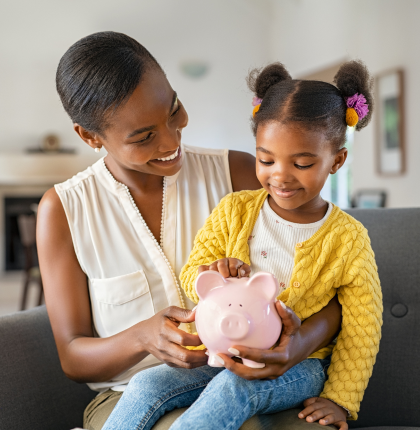 Child adding money to piggy bank with Mother.
