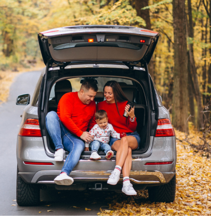 Family in back of open car trunk in the fall.