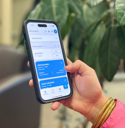 Hand holding a phone displaying Champion CU mobile app.