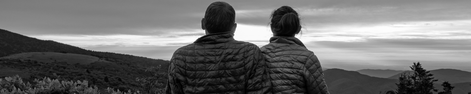 Couple sitting while looking into distance in the mountains.