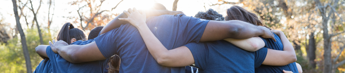 Group of people huddled together with arms around each other.