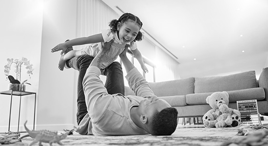 Dad playing with young daughter in living room.