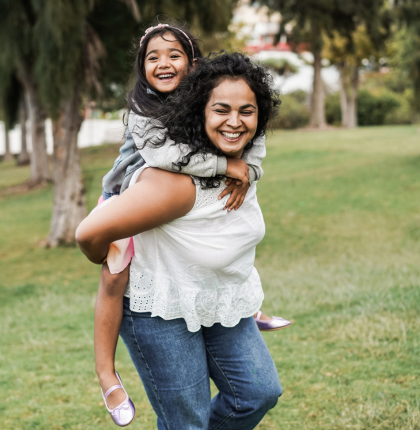 Happy Mother giving Daughter piggyback ride.