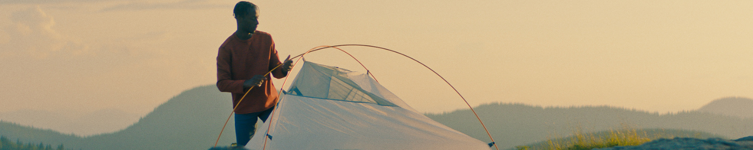 Man setting up tent on mountain.