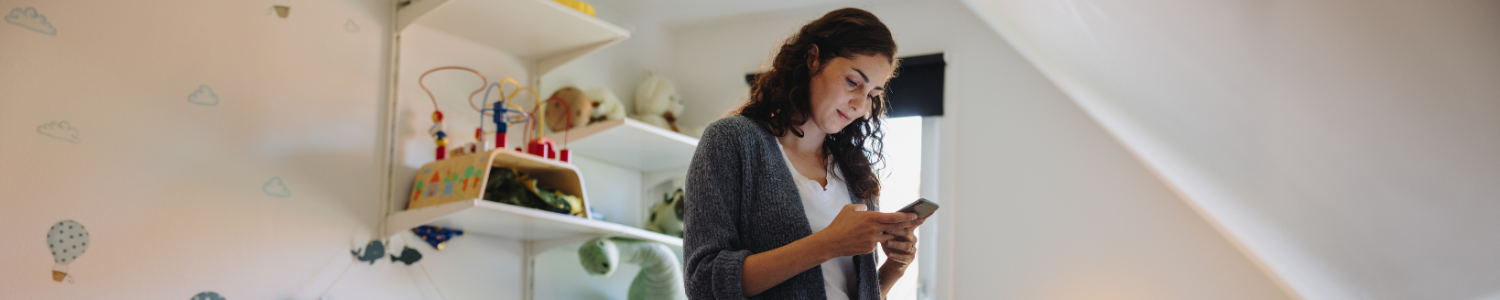 Woman looking at her phone in nursery. 
