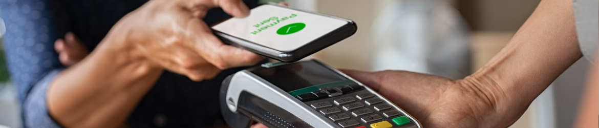 Hand holding phone over card reader to tap-to-pay.
