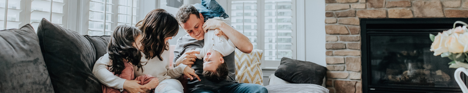 Family hugging on couch in living room.