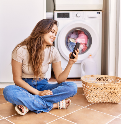 Woman looking at phone in laundry room.