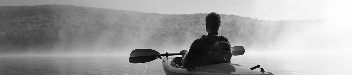 Man kayaking in misty lake