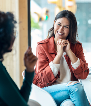 Woman with folded hands smiling with person.