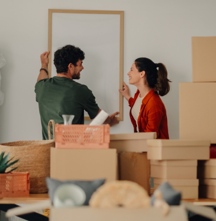 Young happy couple hanging picture frame on wall.