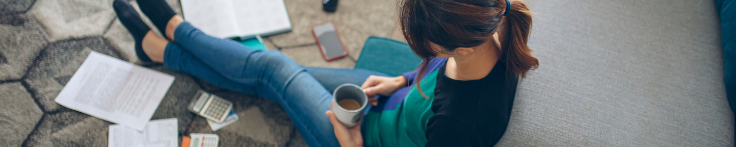 Woman sitting on floor with coffee and scattered papers