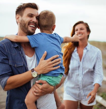 Happy parents holding child while walking. 