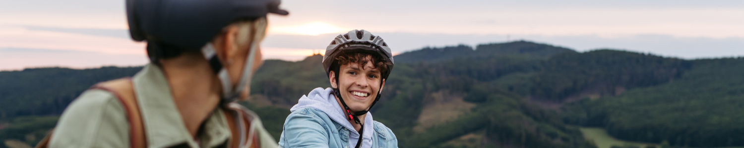 Teenager and parent biking on mountain top.